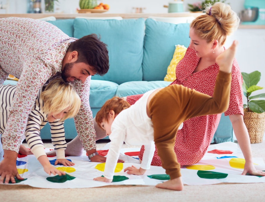 A family with young children playing Twister.