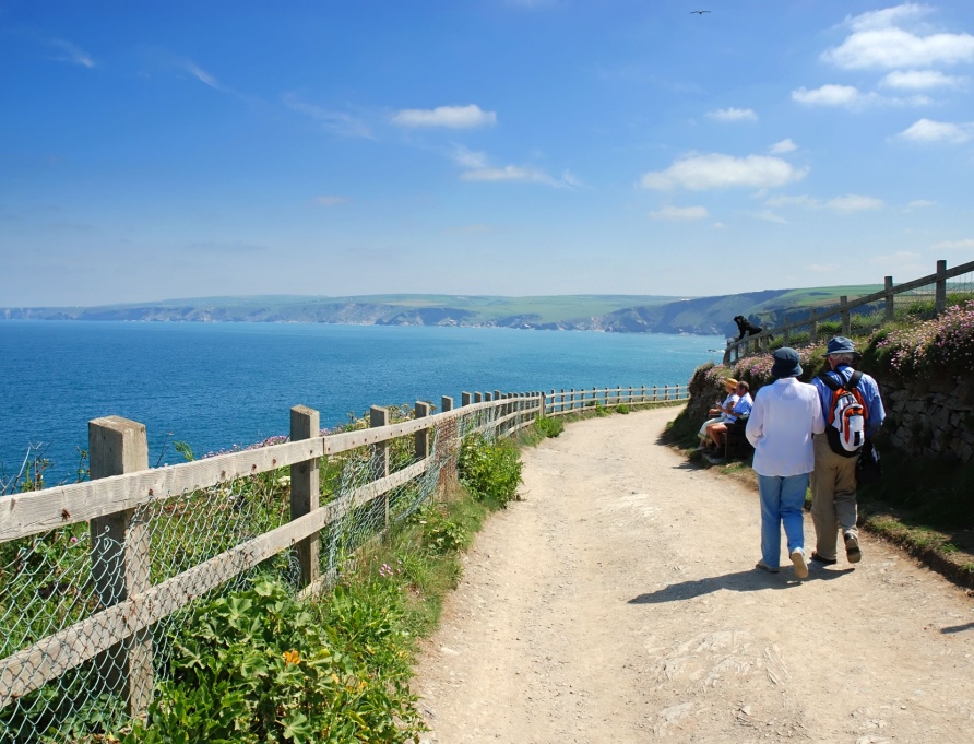 Two people walking along the coast in Port Isaac, Cornwall