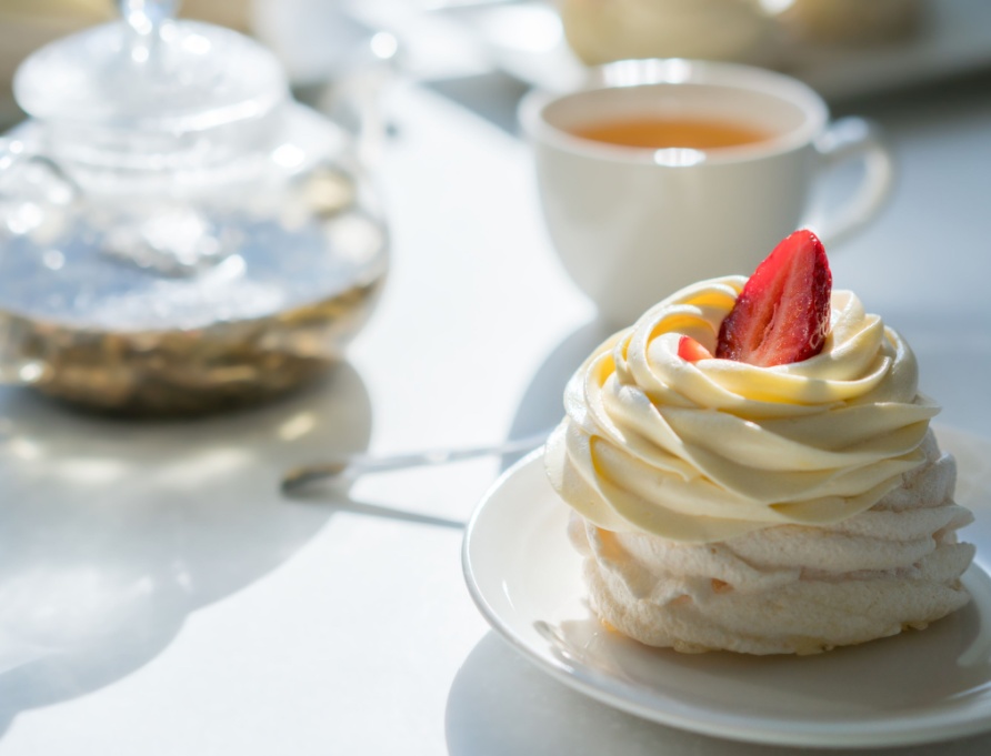 A cream cake on a table with a cup of tea.