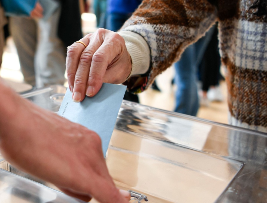 A person putting a ballot paper into a box.