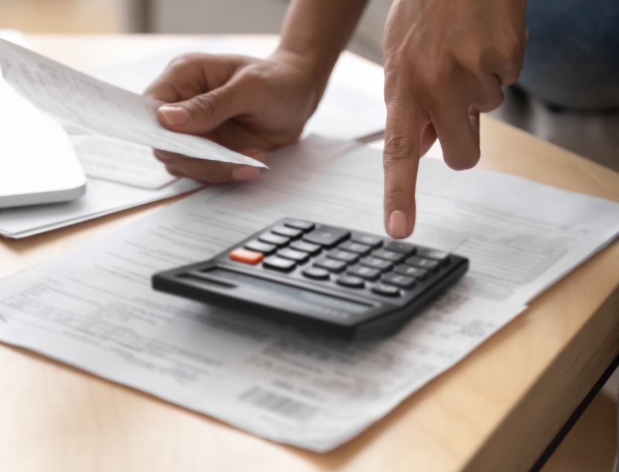 A person going through paperwork with a calculator.