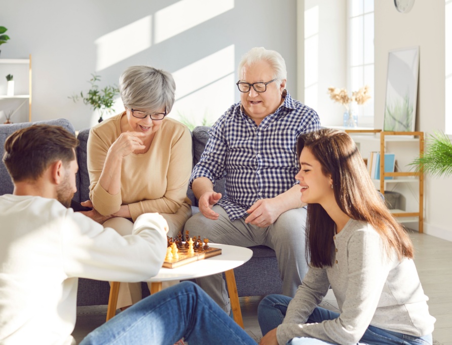 Parents with grown-up children playing chess together.