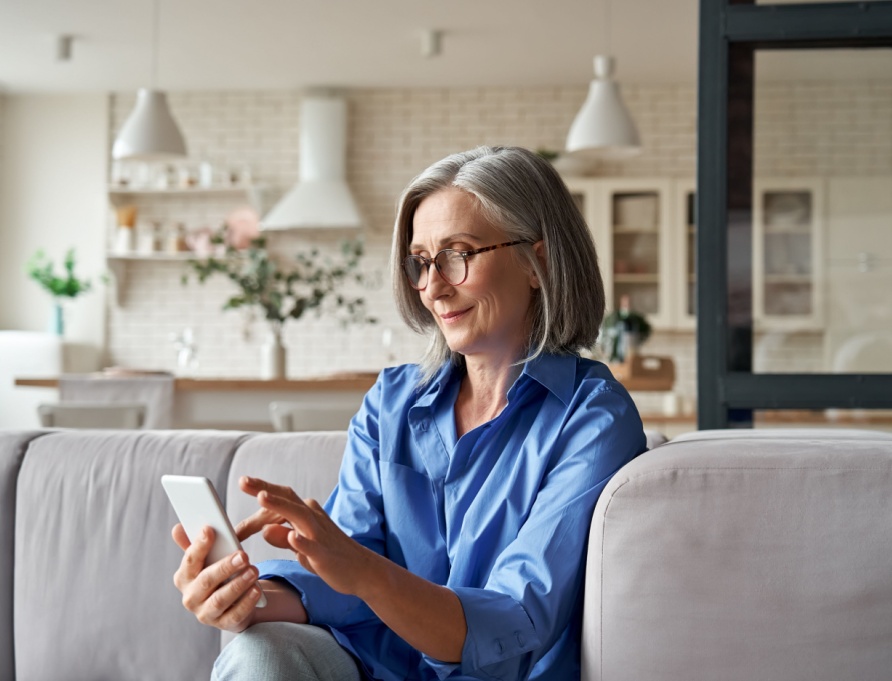 A woman in her 60s checking something on her mobile phone.