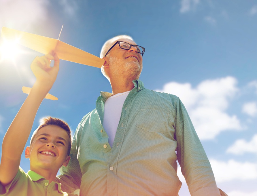 A grandfather and grandson playing with a toy plane outdoors.